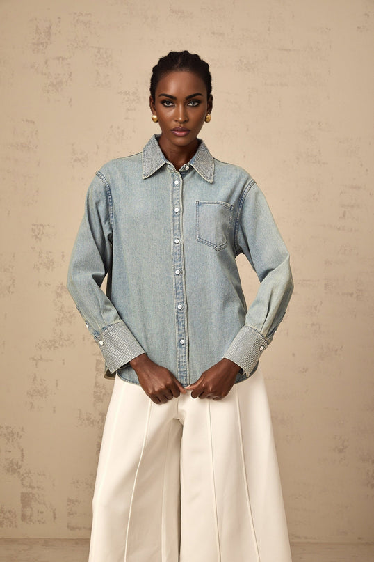 Woman wearing light blue denim shirt with shiny rhinestone embellishments on collar and pockets