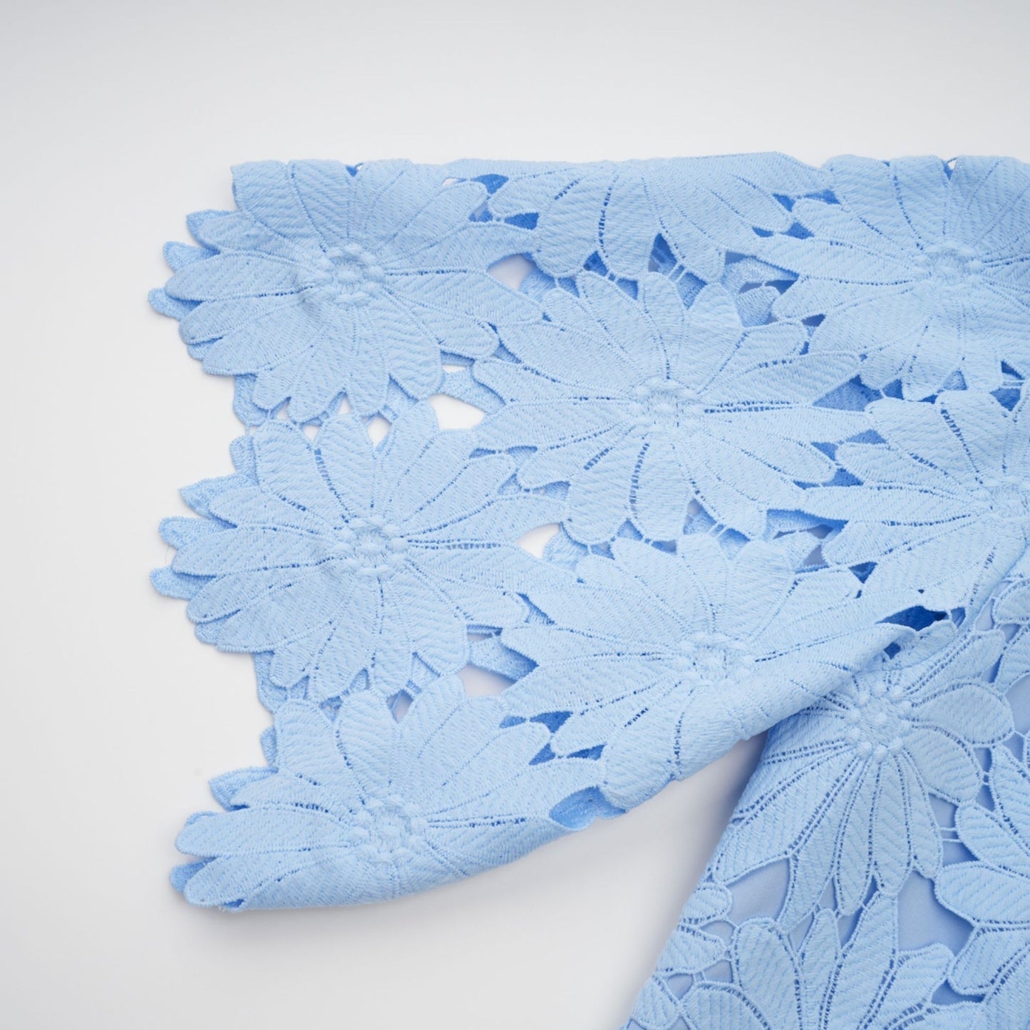 Woman wearing light blue lace top and matching skirt set named Audrey featuring delicate guipure lace pattern