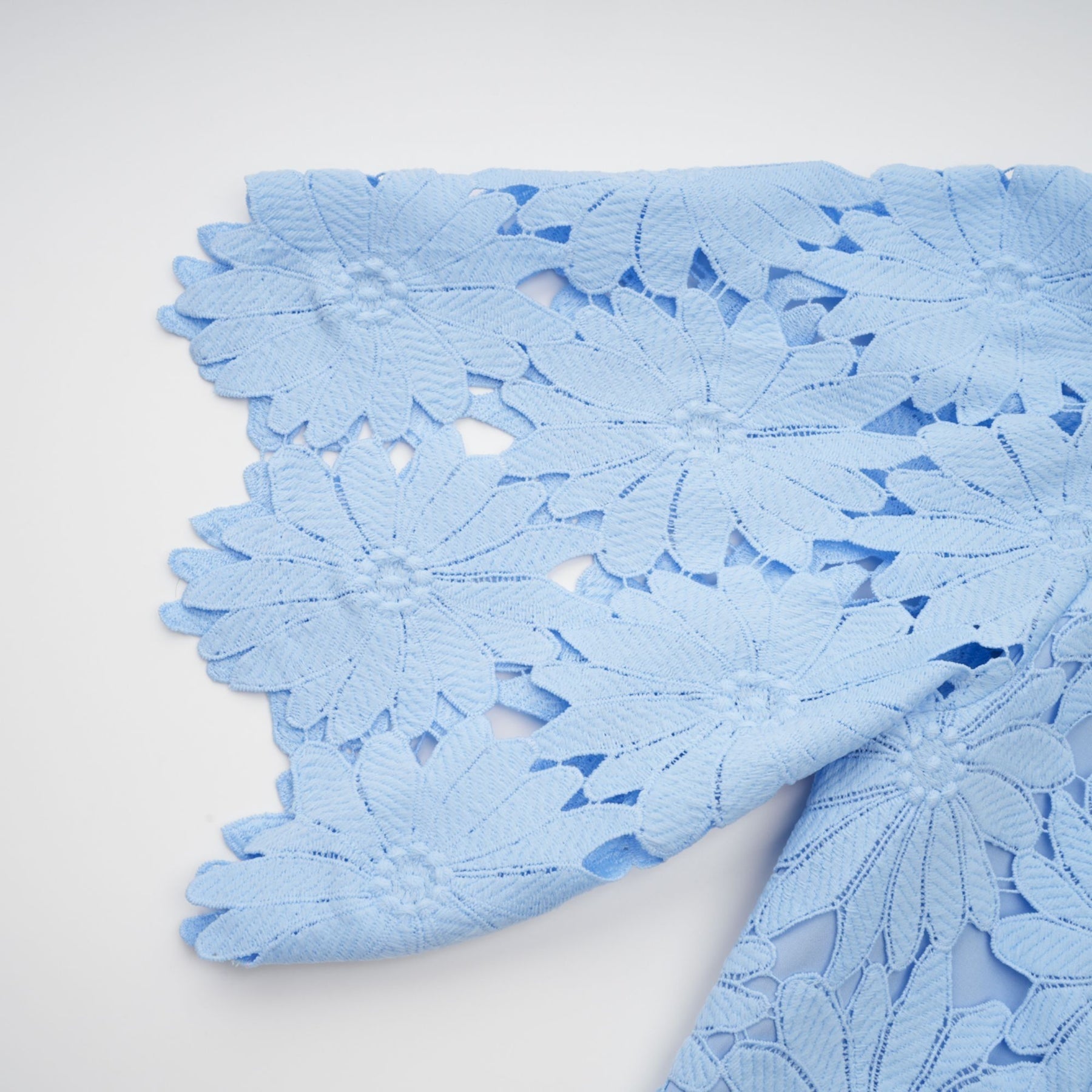 Woman wearing light blue lace top and matching skirt set named Audrey featuring delicate guipure lace pattern