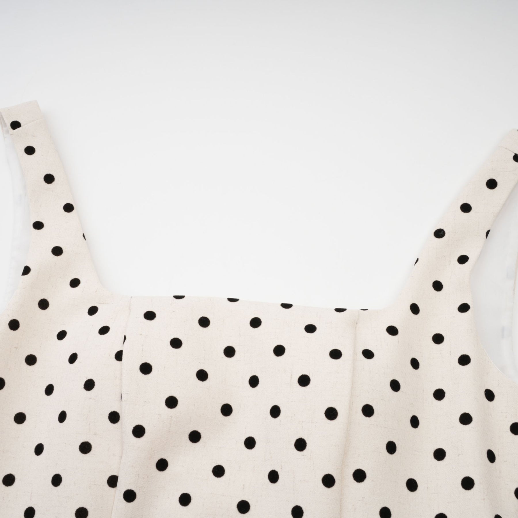 Woman wearing light colored polka dot mini dress with puffed sleeves and gathered skirt