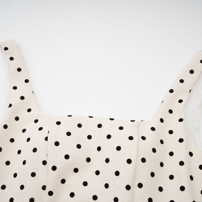 Woman wearing light colored polka dot mini dress with puffed sleeves and gathered skirt