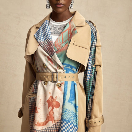 Woman wearing long beige trench coat with contrasting black details and belt tied at waist