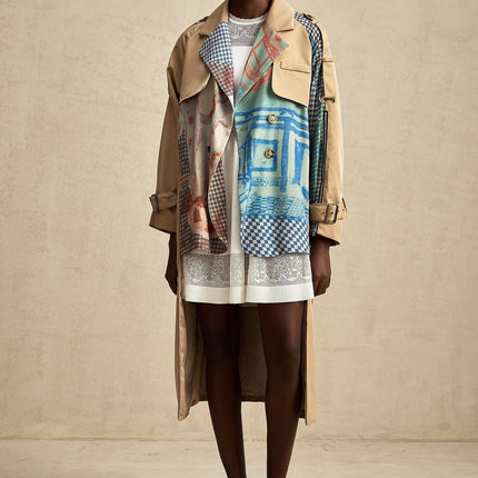 Woman wearing long beige trench coat with contrasting dark trim belt and printed pattern