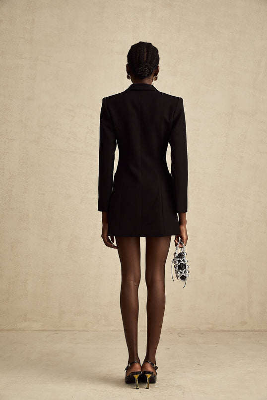 Woman wearing long black blazer dress with lapels and single button closure