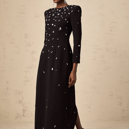 Woman wearing long black evening gown with crystal embellishments and flowing skirt