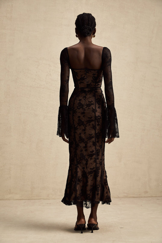Woman wearing long black lace maxi dress with flared silhouette and Marlene style