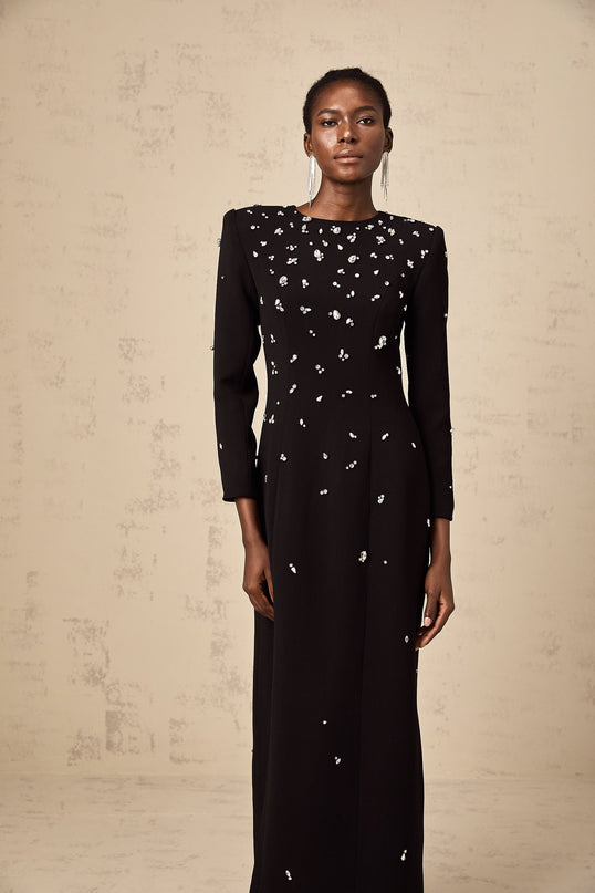 Woman wearing long black maxi dress with crystal embellishments and flowing silhouette