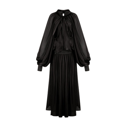 Woman wearing long black pleated satin maxi dress with flowing skirt and fitted bodice