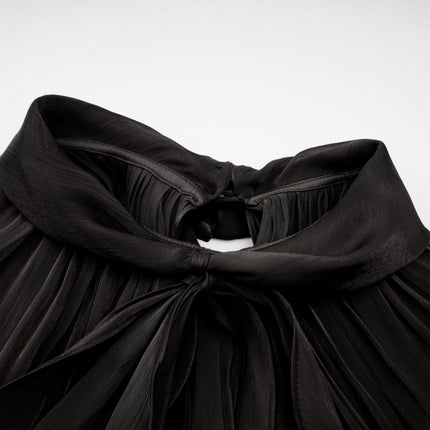 Woman wearing long black pleated satin maxi dress with flowing skirt and fitted bodice