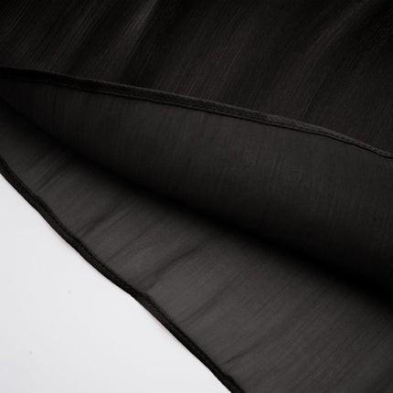 Woman wearing long black pleated satin maxi dress with flowing skirt and fitted bodice