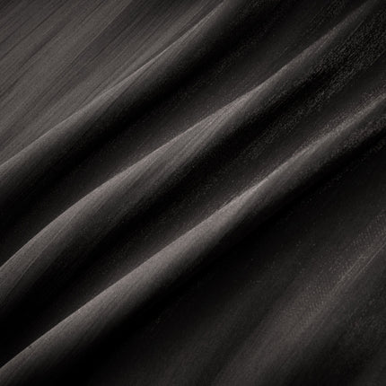 Woman wearing long black pleated satin maxi dress with flowing skirt