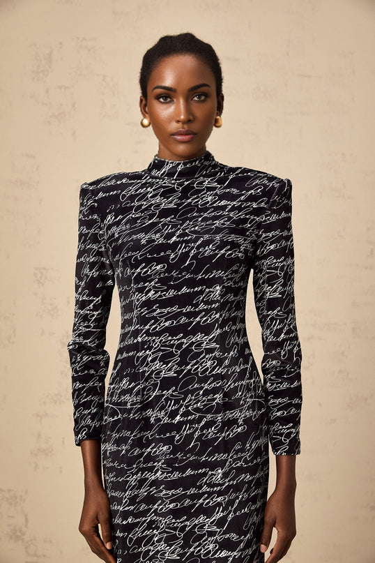 Woman wearing long black velvet maxi dress with jade green letter print design