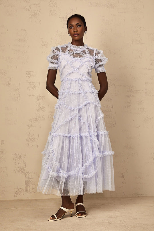 Woman wearing long blue maxi dress with white polka dots and ruffled tulle details