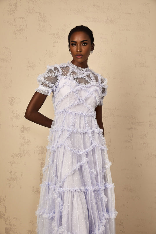 Woman wearing long blue maxi dress with white polka dots and ruffled tulle details