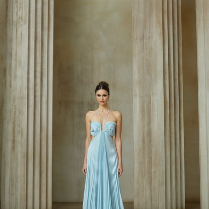 Woman wearing long blue pleated maxi dress with cutout detail standing in relaxed pose