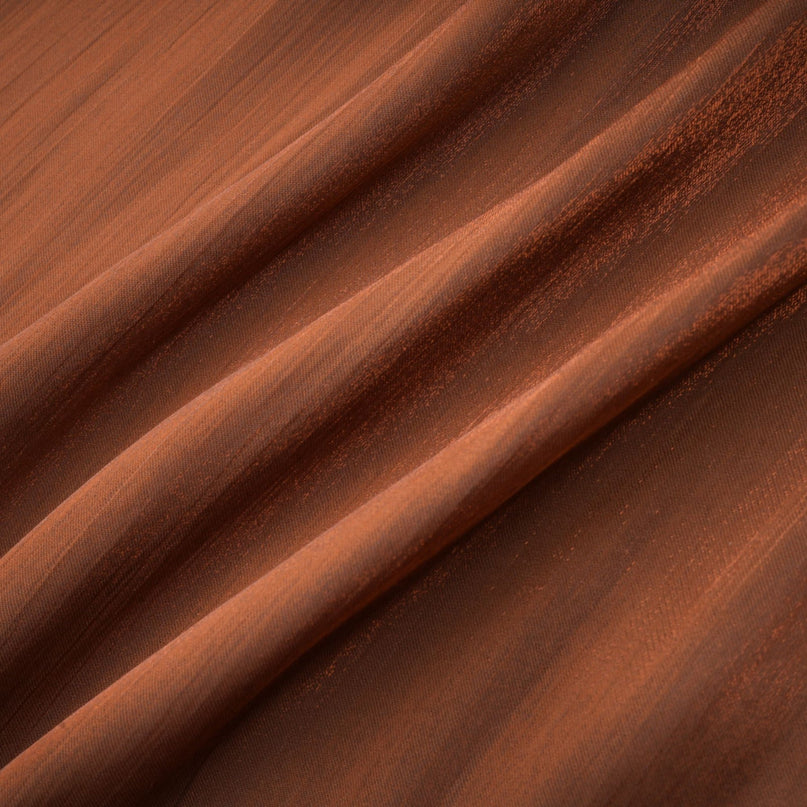 Woman wearing long brown pleated satin maxi dress with flowing skirt and sleeveless design