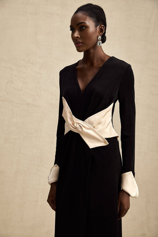 Woman wearing long flowing maxi dress with contrasting colors and bow detail at vneckline