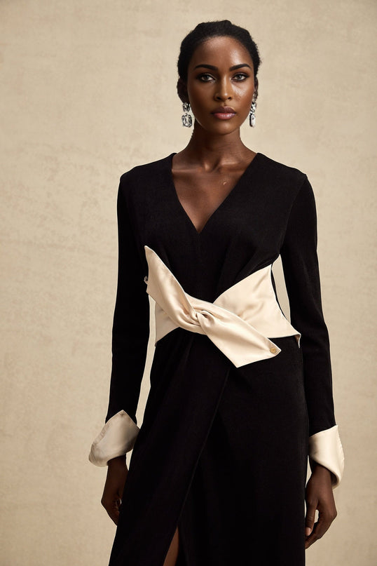 Woman wearing long flowing maxi dress with contrasting colors and bowknot detail at vneckline