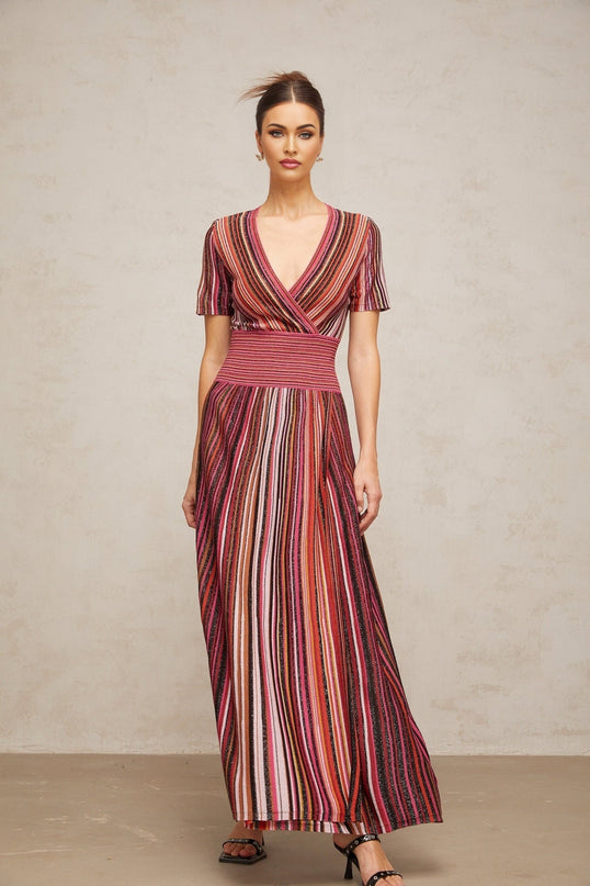 Woman wearing long flowing multicolor metallic knit maxi dress with shimmering fabric and sleeveless design