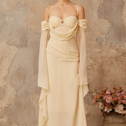 Woman wearing long flowing neutral colored chiffon maxi dress with ruched details