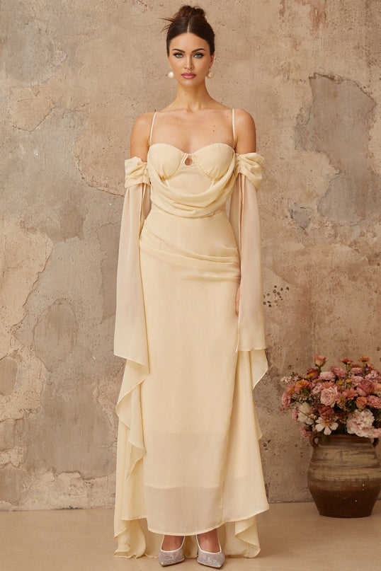 Woman wearing long flowing neutral colored chiffon maxi dress with ruched details