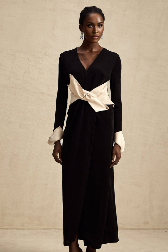 Woman wearing long flowy maxi dress with contrasting colors and a decorative bow at the v neckline