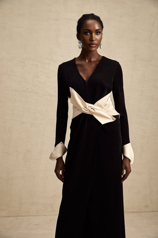 Woman wearing long flowy maxi dress with contrasting colors and bow detail at v neckline