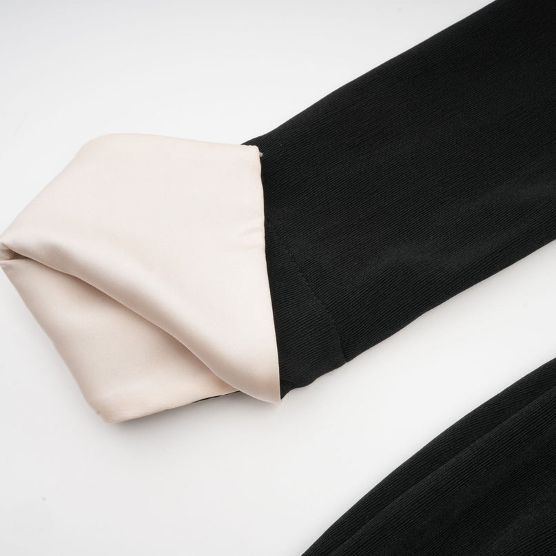 Woman wearing long flowy maxi dress with contrasting colors and bowknot detail at vneckline