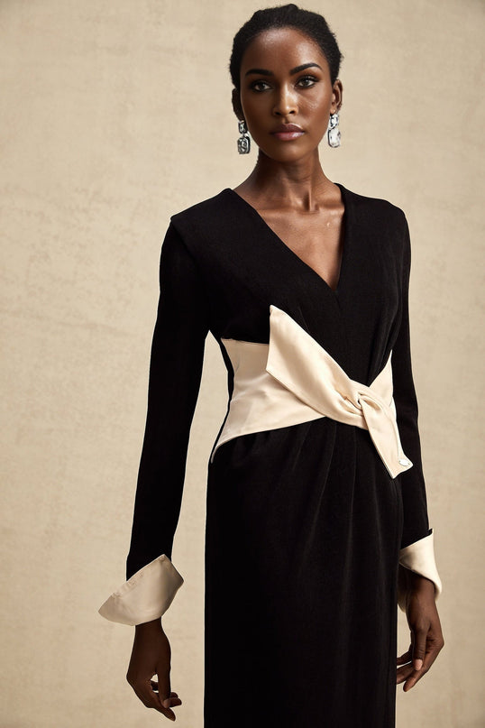 Woman wearing long flowy maxi dress with contrasting colors and large bow detail at v neckline