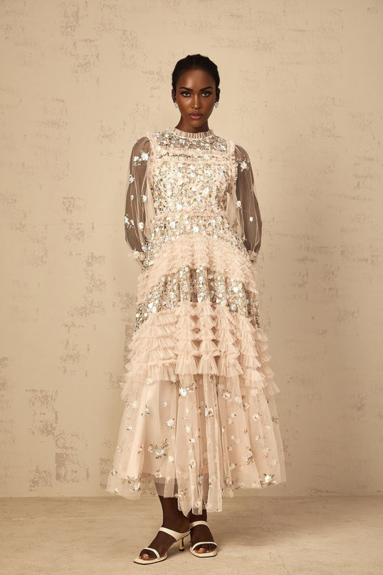 Woman wearing long flowy maxi dress with floral embroidery and tiered tulle skirt