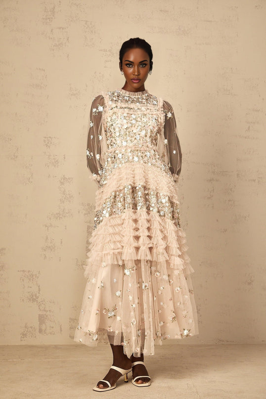 Woman wearing long flowy maxi dress with floral embroidery and tiered tulle skirt