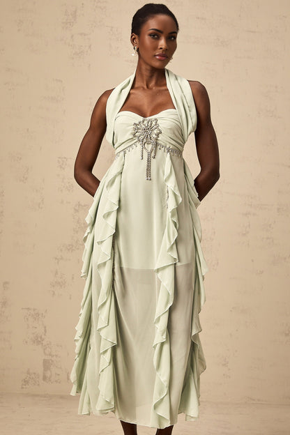 Woman wearing long flowy midi dress with embellished details and ruffled accents