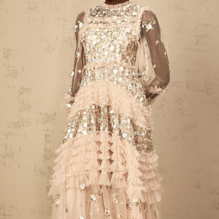 Woman wearing long flowy tulle maxi dress with floral embroidery and tiered skirt design