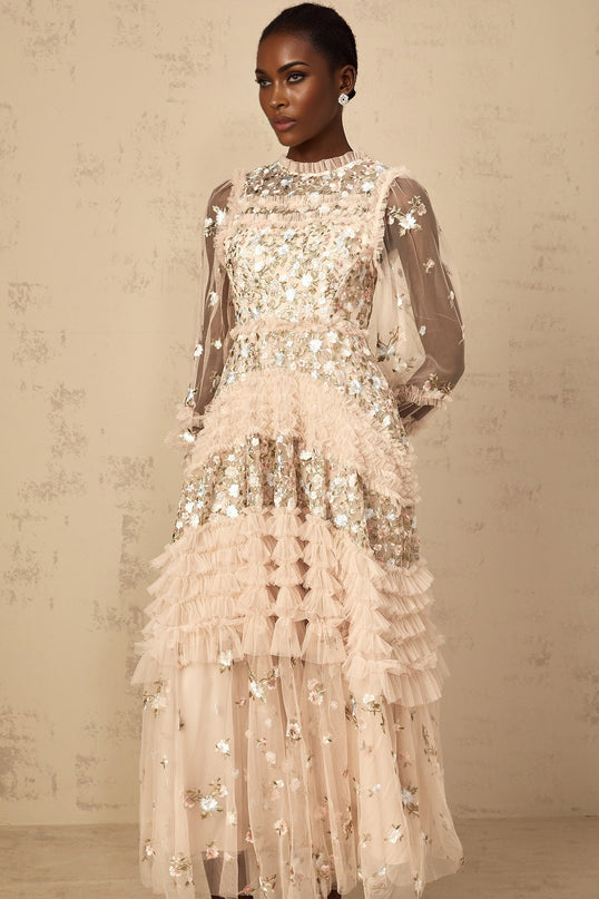 Woman wearing long flowy tulle maxi dress with floral embroidery and tiered skirt design