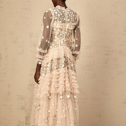 Woman wearing long flowy tulle maxi dress with floral embroidery and tiered skirt design