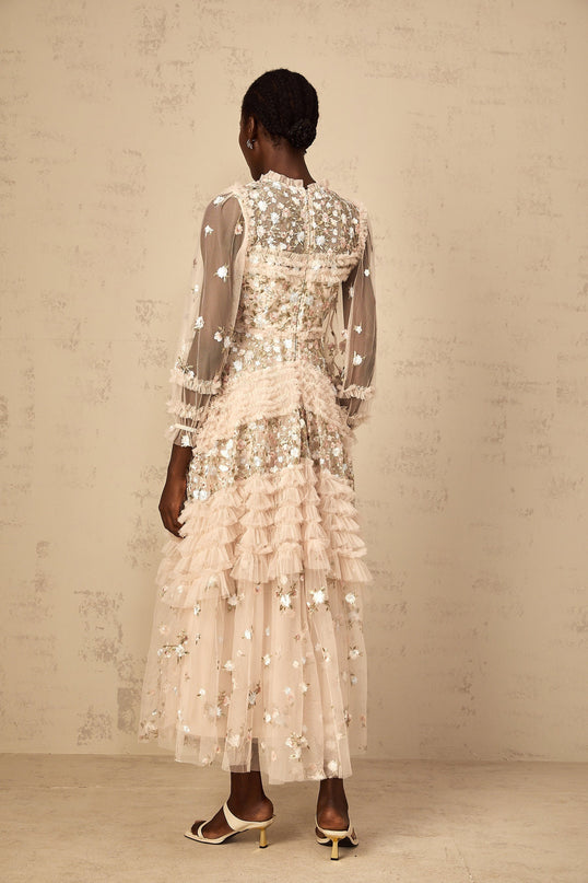 Woman wearing long flowy tulle maxi dress with floral embroidery and tiered skirt design