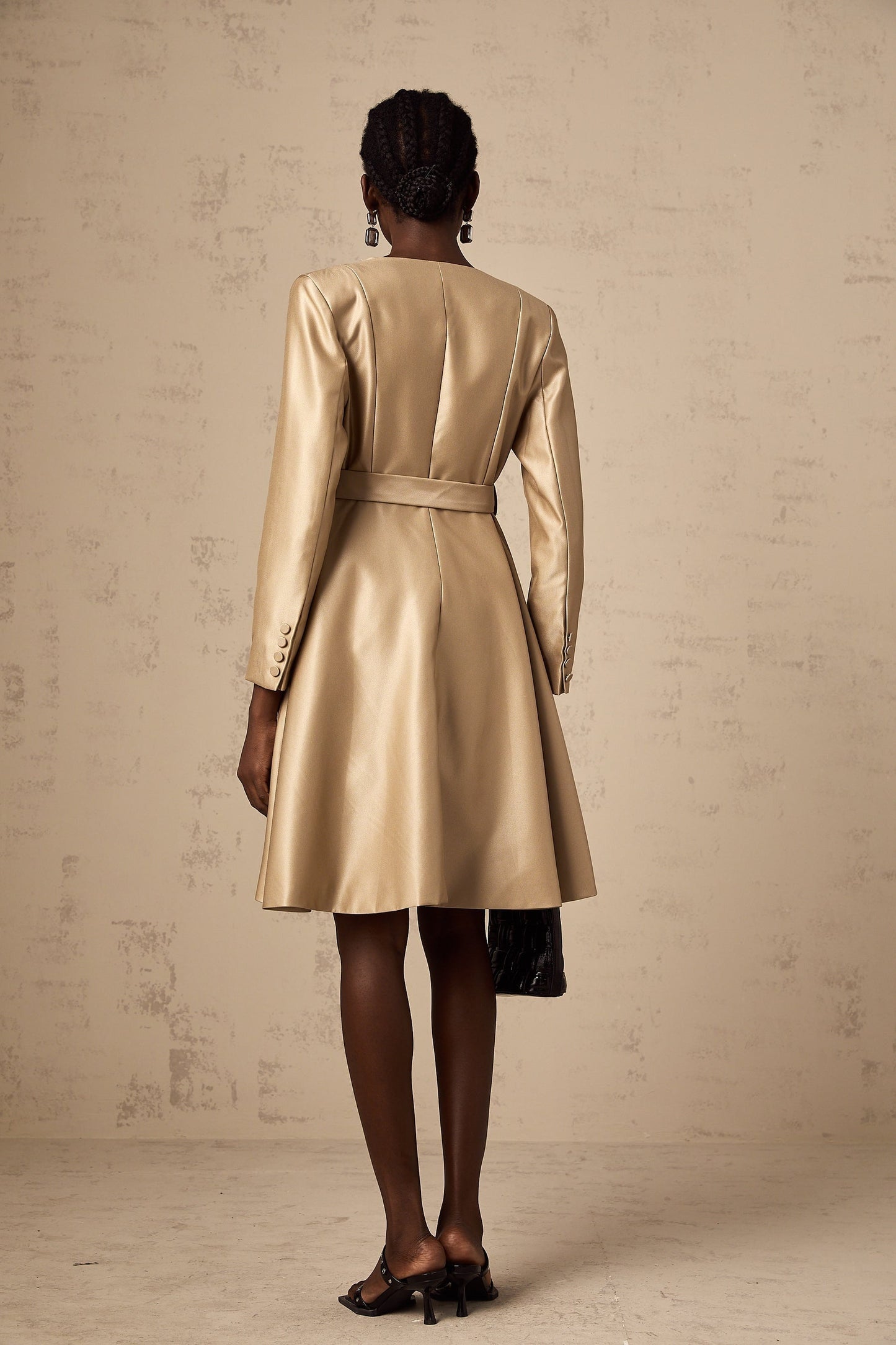 Woman wearing long khaki coat with belt at waist and open front