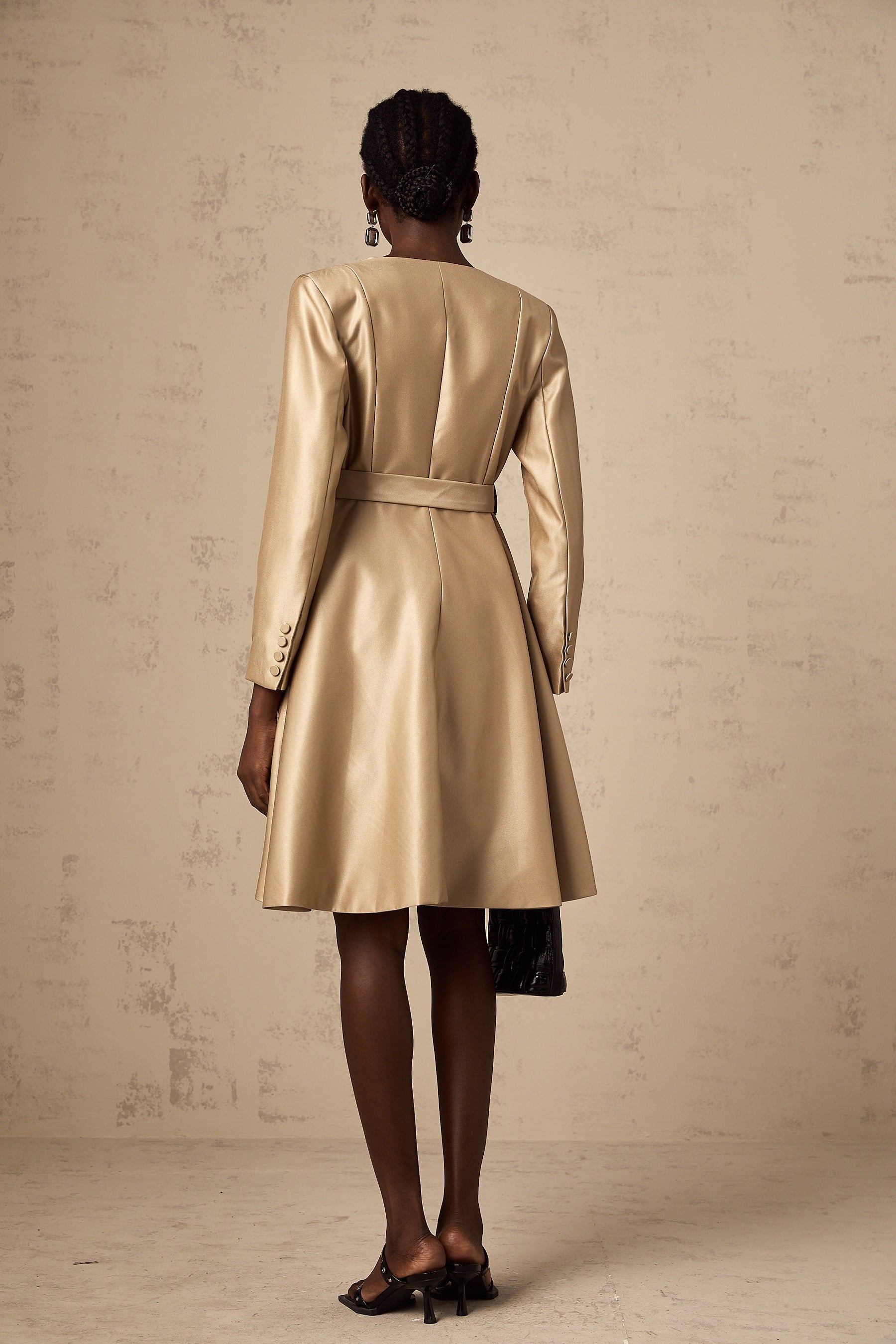 Woman wearing long khaki coat with belt at waist and open front