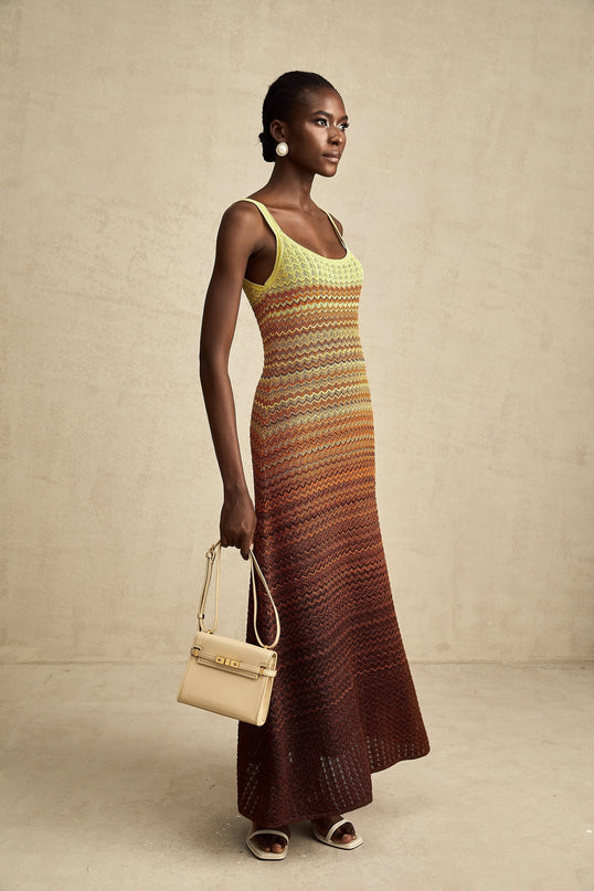 Woman wearing long knitted maxi dress with gradient color pattern from light to dark