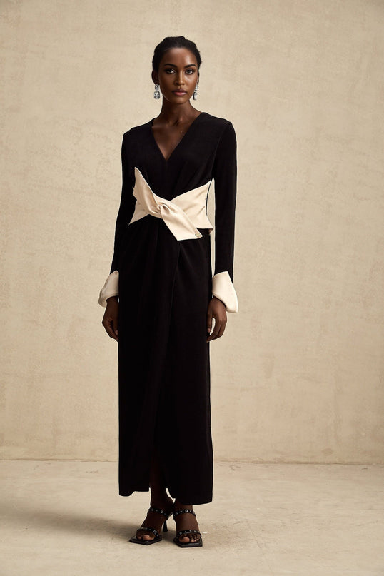 Woman wearing long maxi dress with contrasting colors and bow detail at vneckline