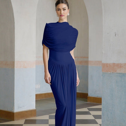Woman wearing long navy blue asymmetric pleated maxi dress with flowing skirt and sleeveless design