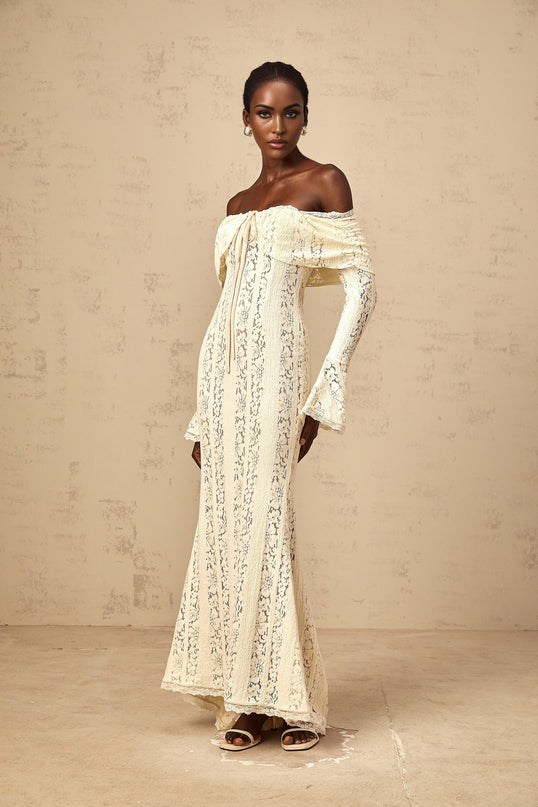 Woman wearing long neutral colored floral lace maxi dress with train design