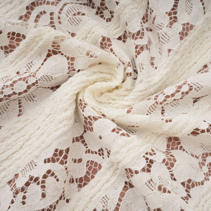 Woman wearing long neutral colored floral lace maxi dress with train design