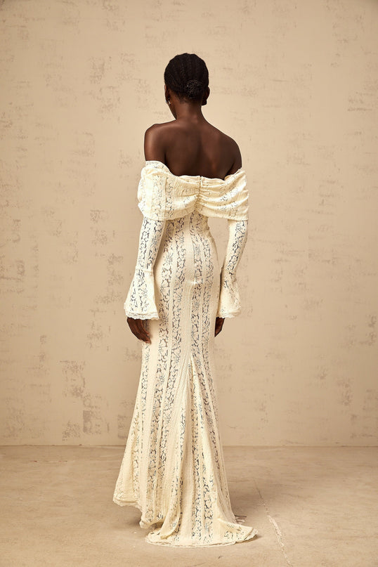 Woman wearing long neutral colored floral lace maxi dress with train design