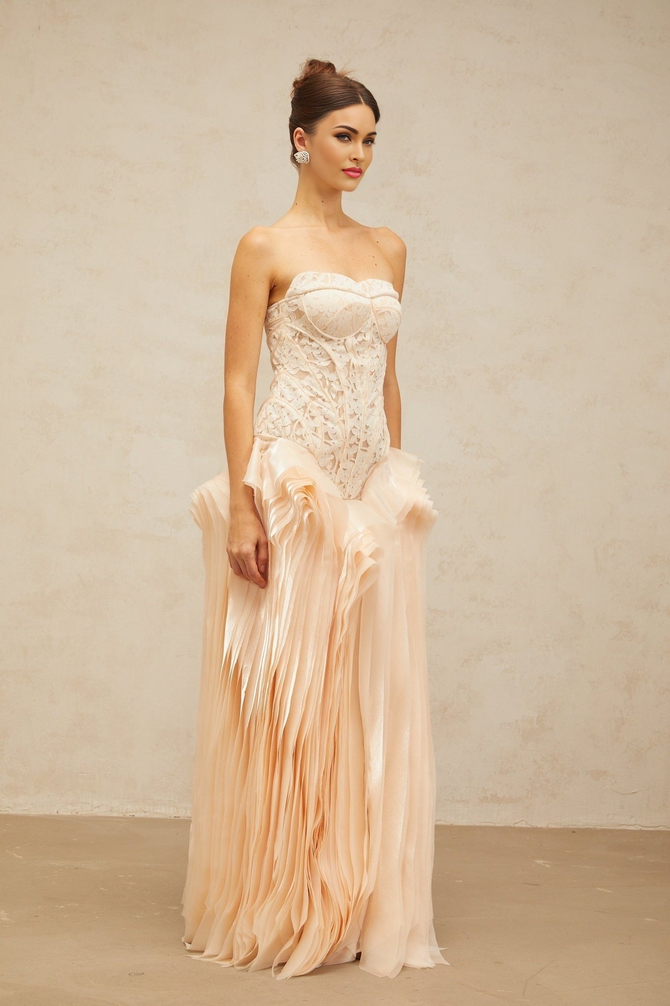 Woman wearing long neutral colored maxi dress with lace overlay and corset style bodice