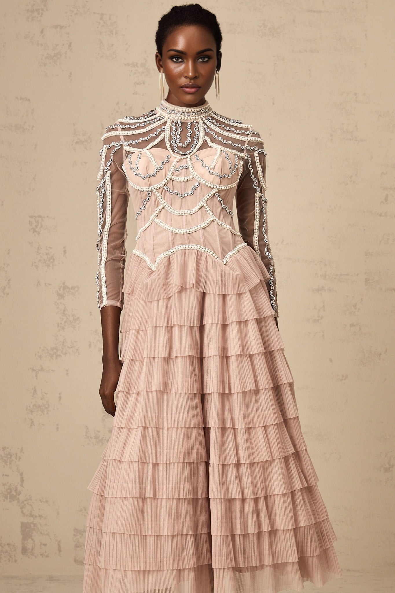 Woman wearing long pink gown with tiered skirt and beaded details semi sheer fabric floor length dress formal evening wear