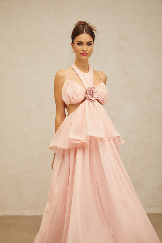 Woman wearing long pink maxi dress with floral applique details and cutout sections