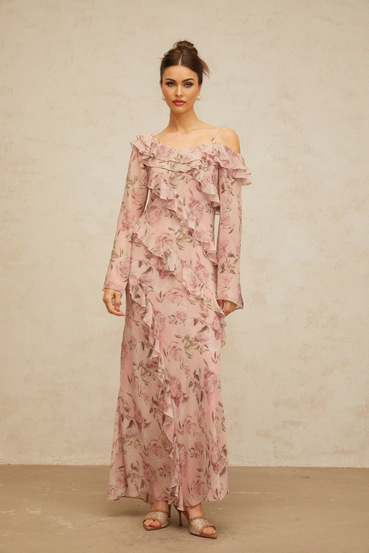 Woman wearing long pink maxi dress with floral print and ruffled details