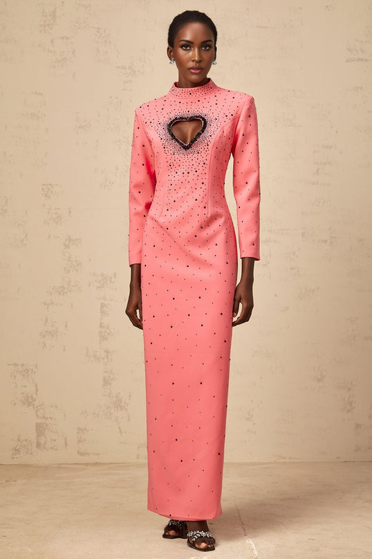 Woman wearing long pink maxi dress with heart shaped cutout and embellishments