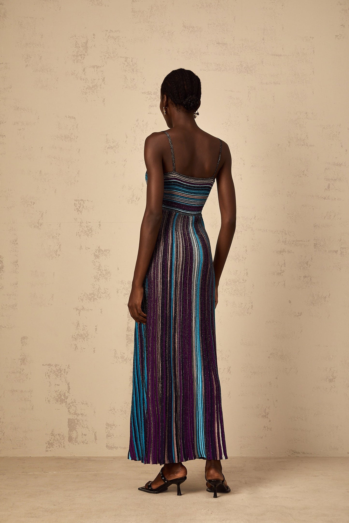 Woman wearing long purple knit maxi dress with shimmering sequin stripes
